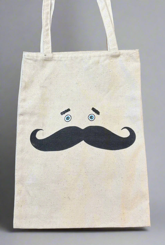 Beige tote bag with a mustache design on a black background
